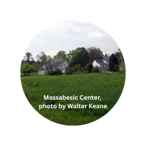 A grassy field leads to the Massabesic Center buildings surrounded by trees.